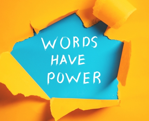 Yellow paper ripped open to reveal blue paper beneath, with words written in white chalk that say Words Have Power